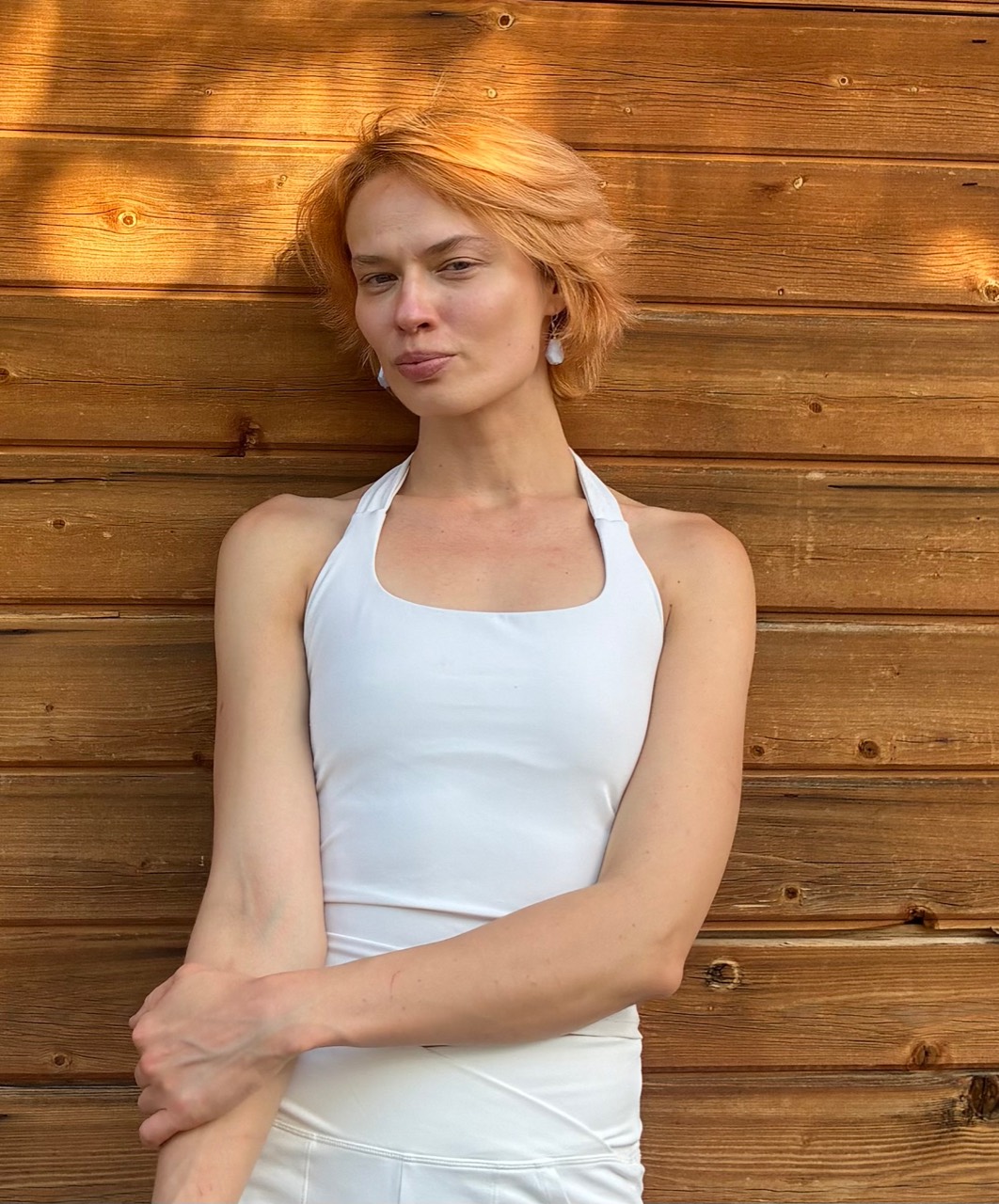 Eugenia standing against a wooden wall